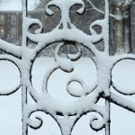 An iron gate on the Elon University campus covered in snow.