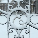 An iron gate on the Elon University campus covered in snow.