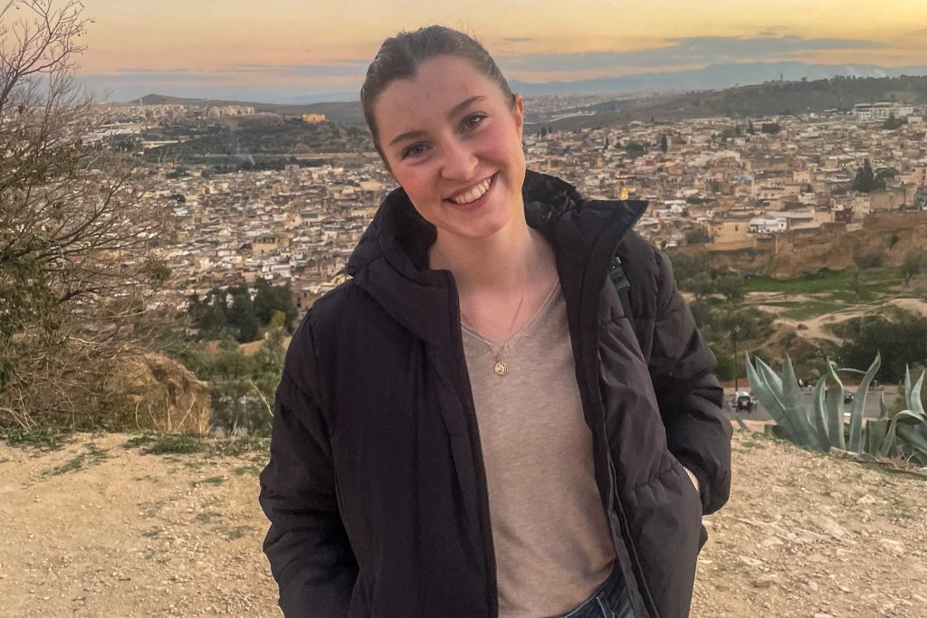 Natalie Triche, an international and global studies major, is a Fulbright Scholar in Morocco. She stands with the city skyline behind her.