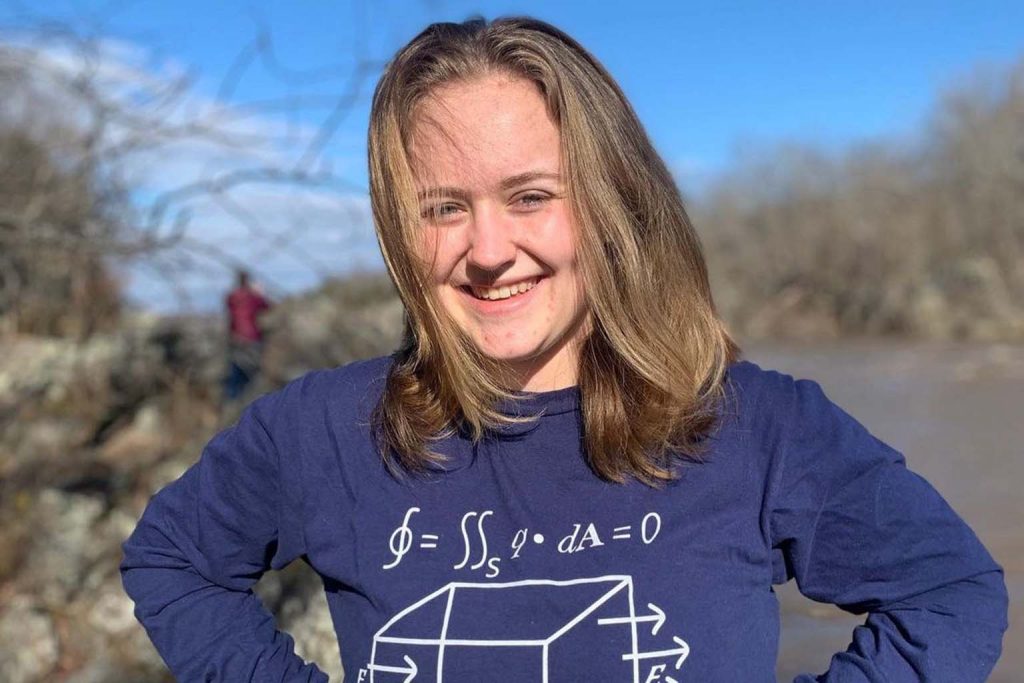 Anne Williams is outside wearing a blue shirt with equations written on it.