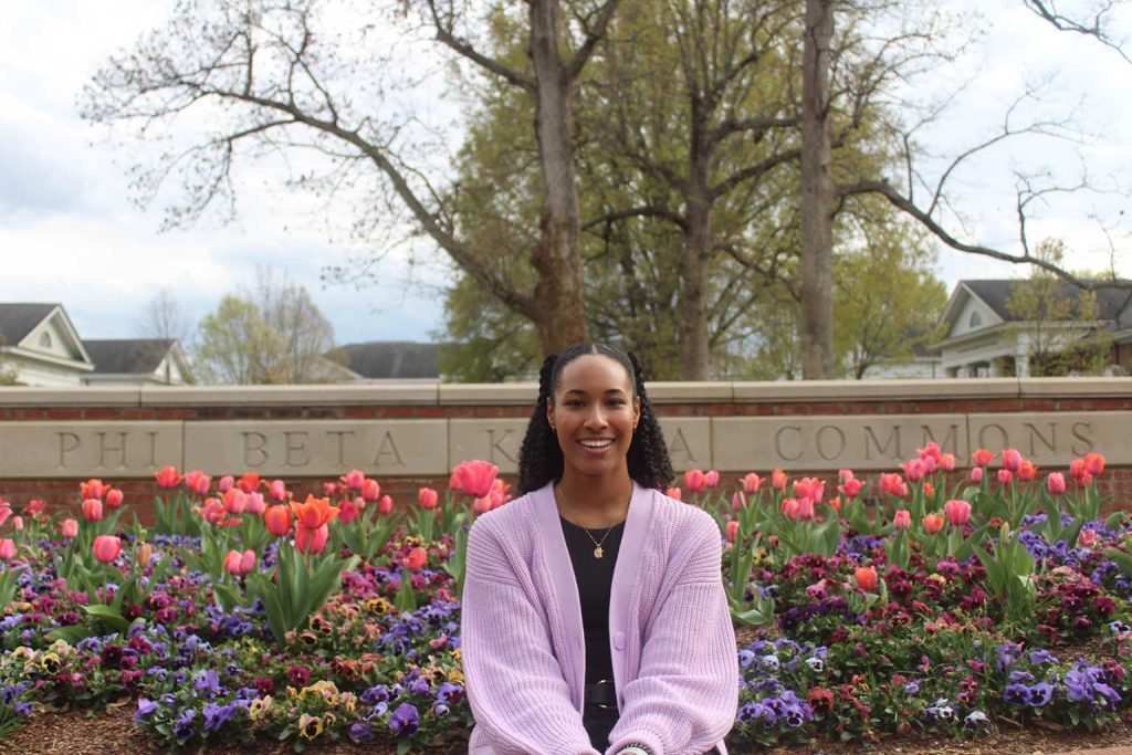 Amaya Gaines sits in front of tulips and colorful flowers on Phi Beta Kappa Commons.