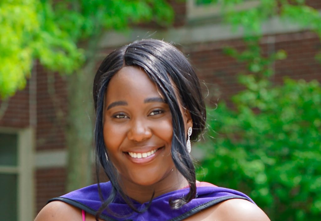 Portrait photo of Mariatu Okonofua wearing a purple hood from a graduate commencement ceremony.