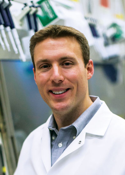 Geoffrey Lynn in a science lab wearing a white lab coat.