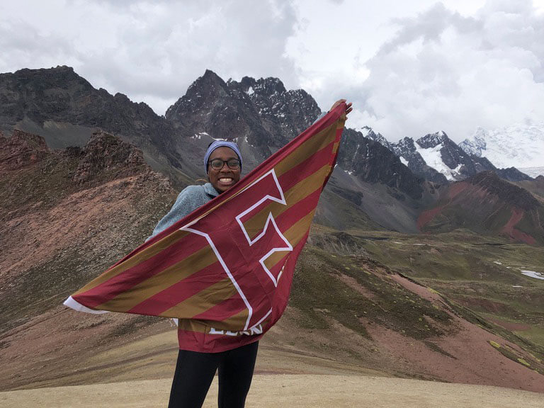 Student holding an Elon flag in front of mountains in Peru.