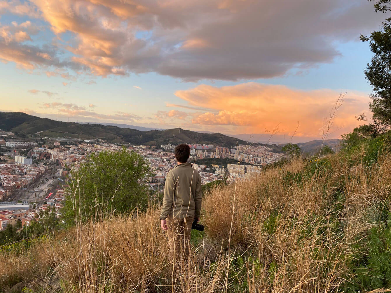 Student on a grass-covered hill overlooking a city while studying abroad.