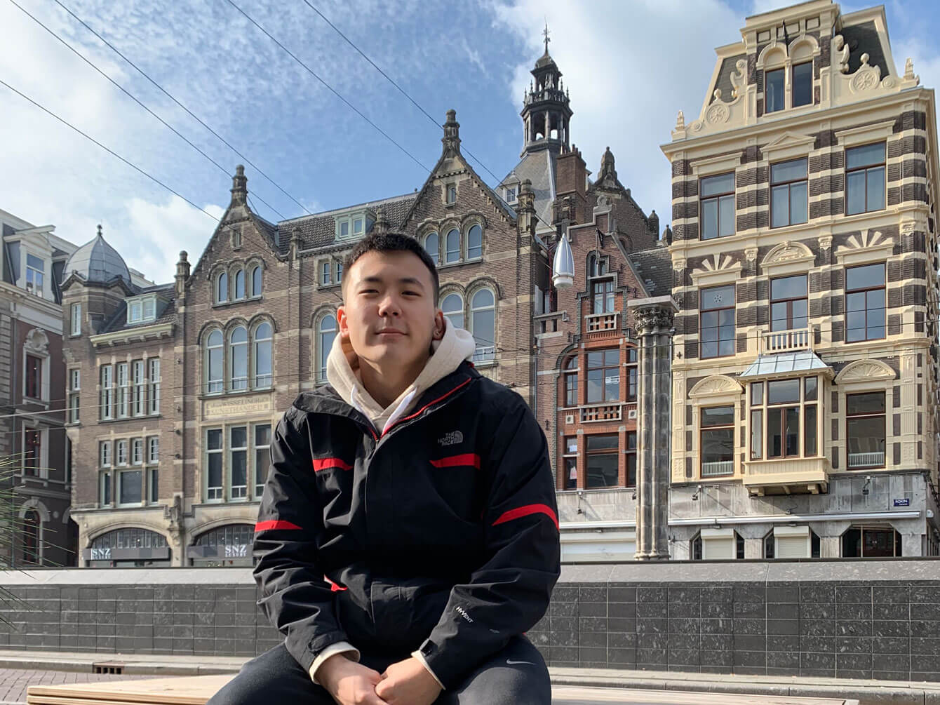 Male student posing for photo in front of buildings while studying abroad.