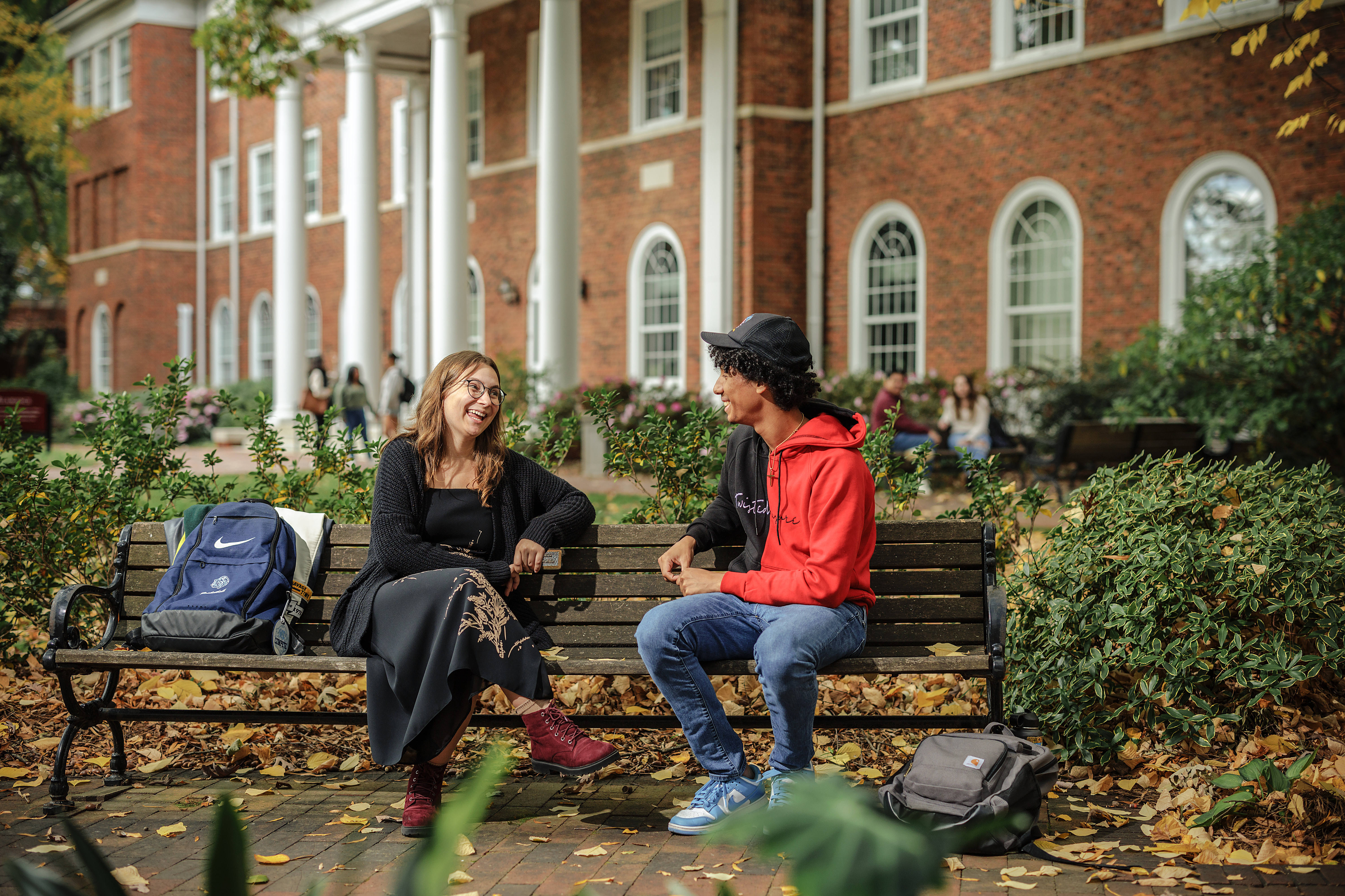 Students chat on a bench in the historic area of campus.
