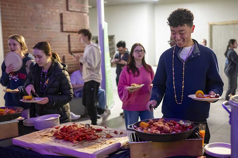 Students are helping themselves to a selection of crawfish, corn on the cob and other food during a Mardi Gras celebration dinner.