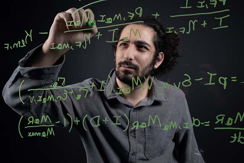 Rony Dahdal writes equations in green ink on a clear board.