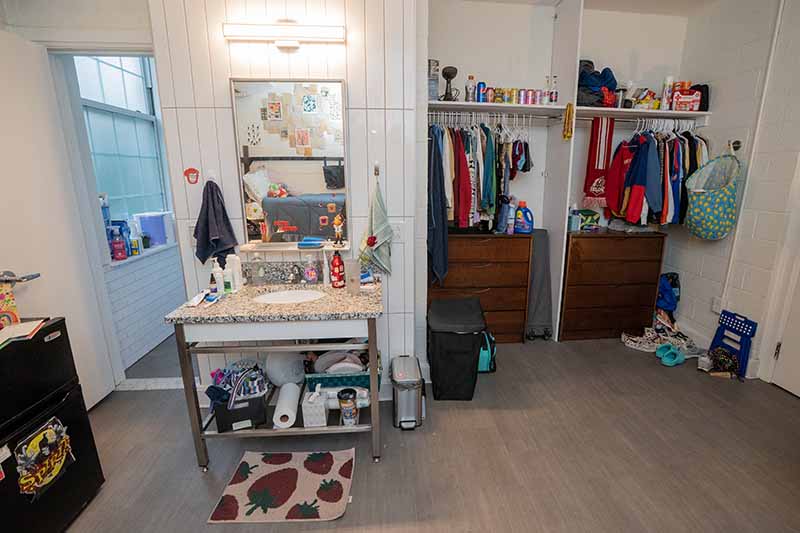 A double room in Virginia Hall with an open closet that has two sides and a dresser in each. There is a sink with a mirror above it just outside the bathroom.