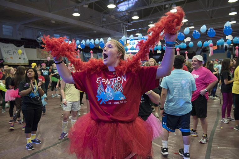Dressed in a red ElonThon shirt and a red tutu, a students sings and dances holding a red boa.