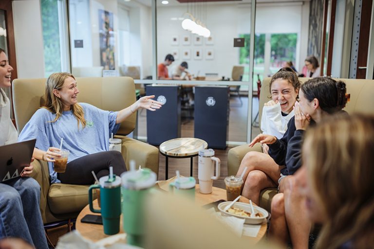 A group of sorority sisters sit in a circle in Acorn Coffee shop laughin.