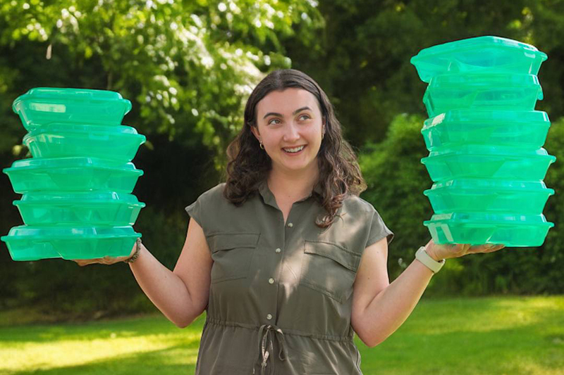 A woman holding clear green reusable to-go containers