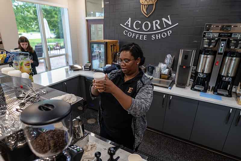 A woman wearing a uniform makes coffee at the Acorn Coffee Shop
