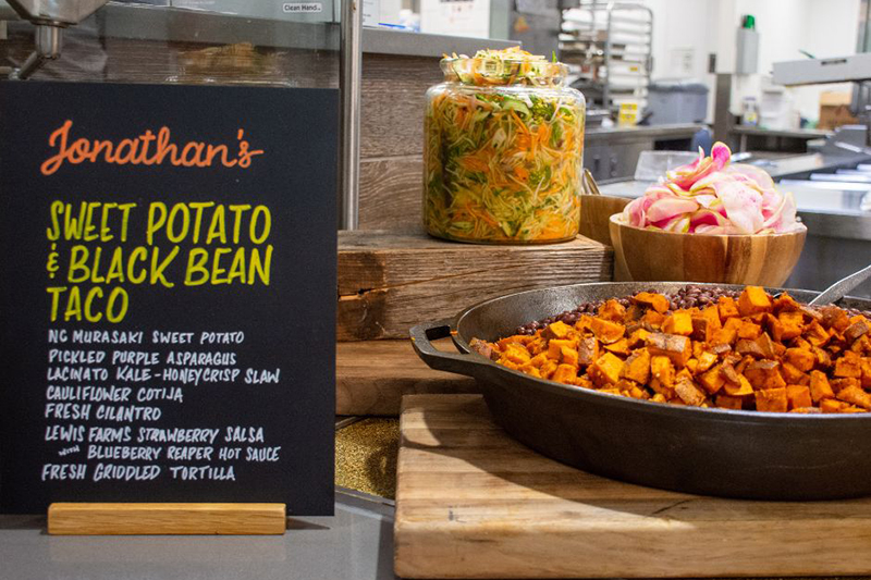 Sweet potato and black bean taco ingredients. A description of the tacoes is on a black sign.