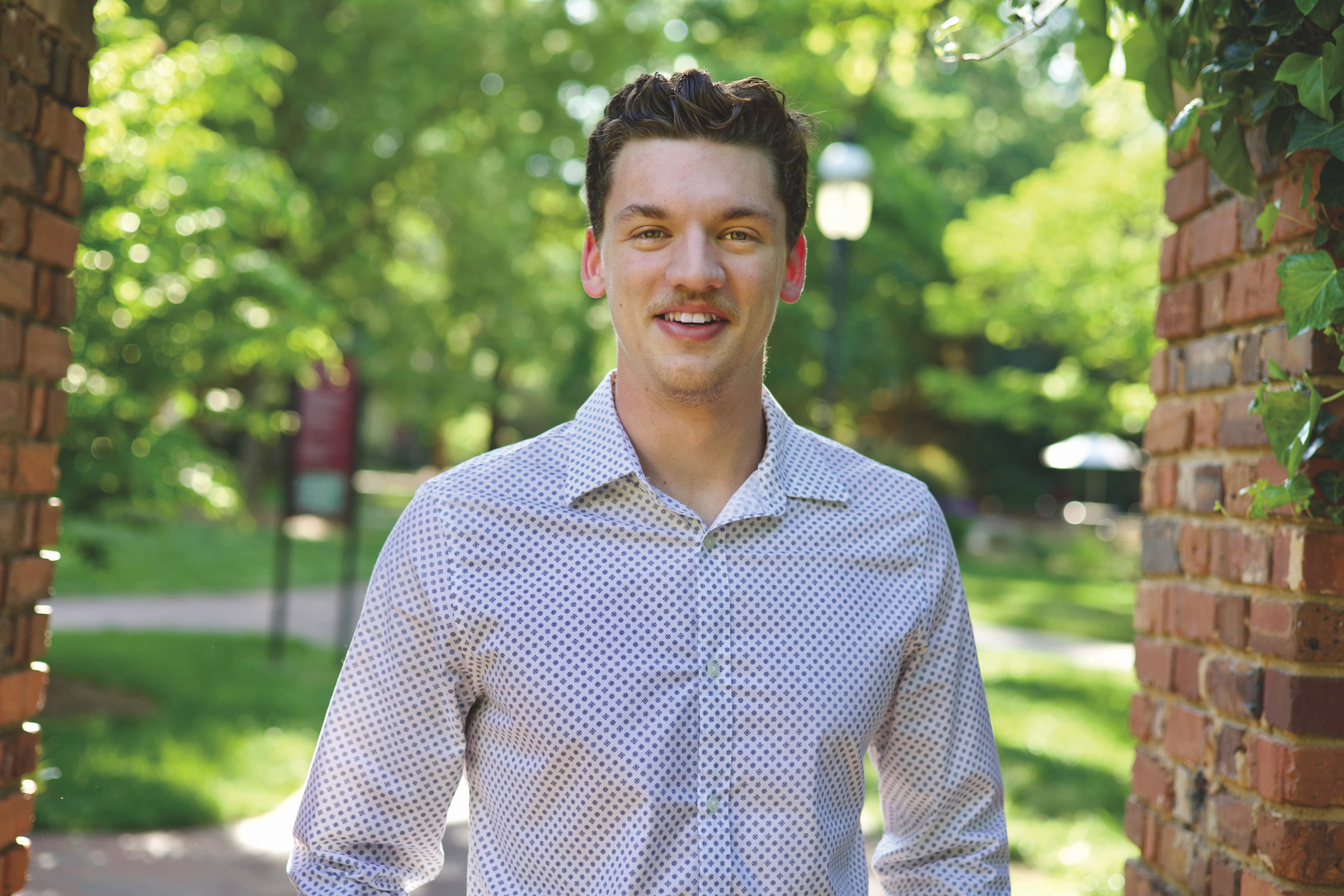 Portrait photo of Nick Muller with green trees in the background.