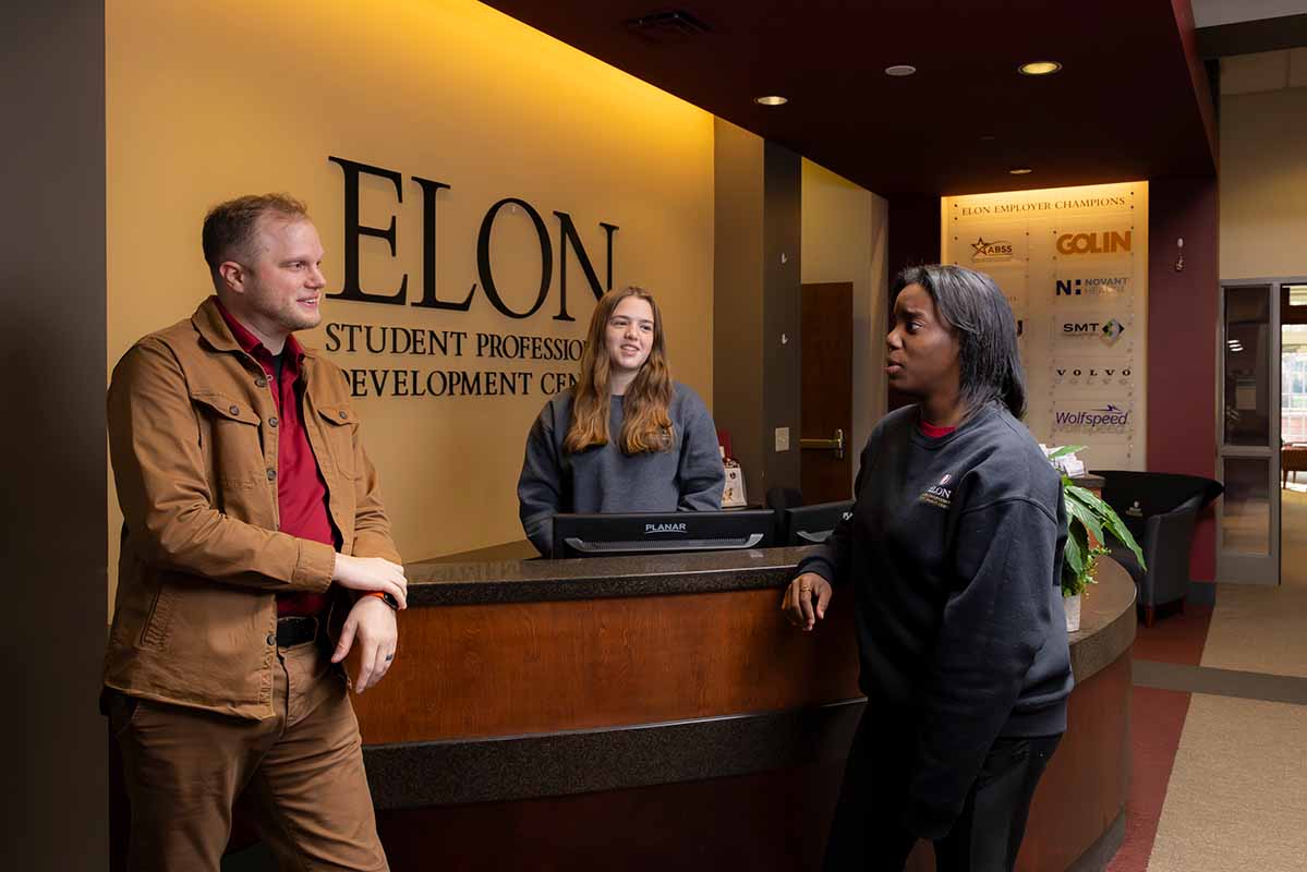 Two students talking with a career adviser at the front desk of the Student Professional Development Center