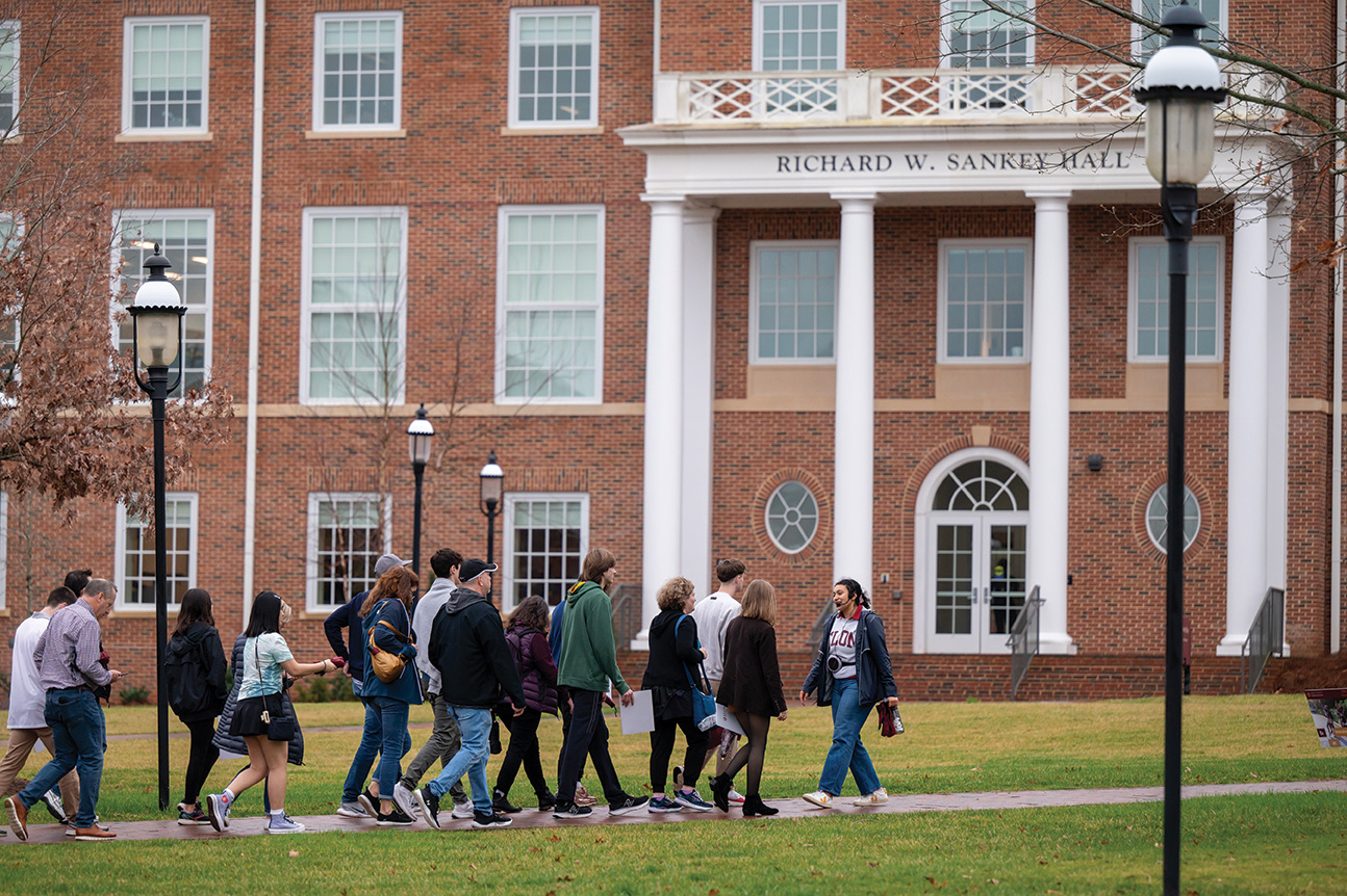A student in an Elon shirt leads a group of people on a tour.
