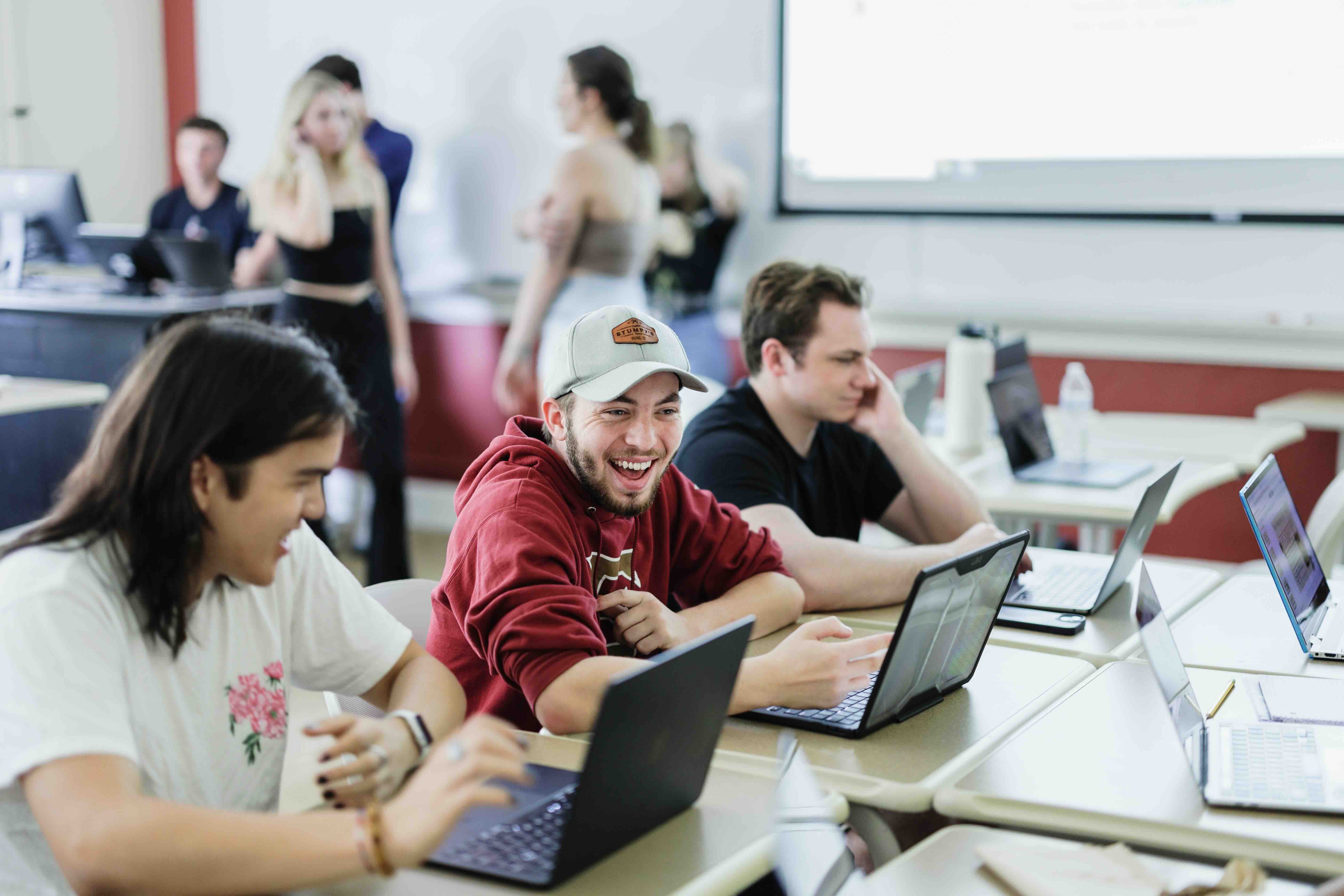 Two students laughing together in a classroom.