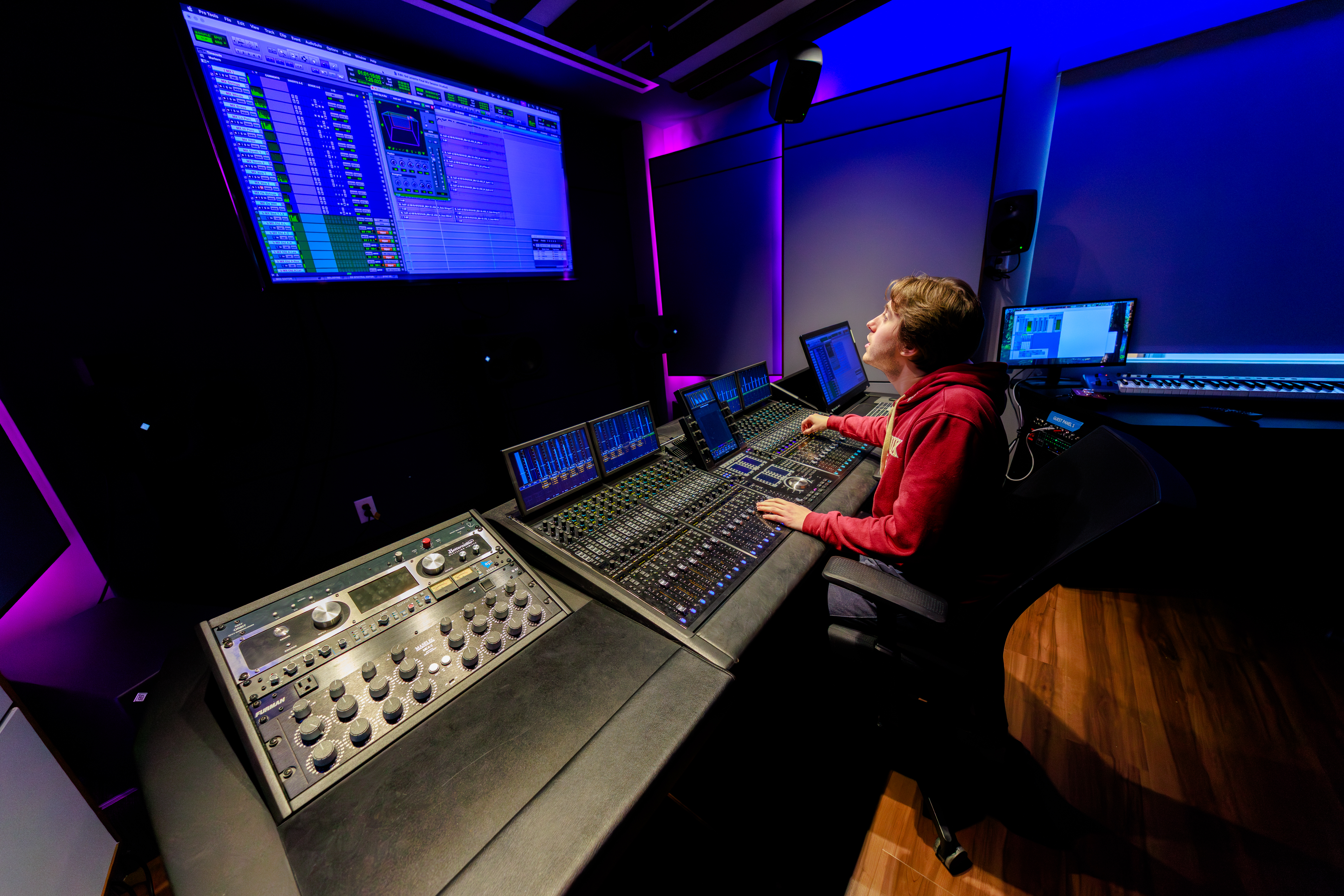 A student works at a sound board in a studio.