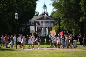 Orientation Leaders holding signs and leading their groups around campus