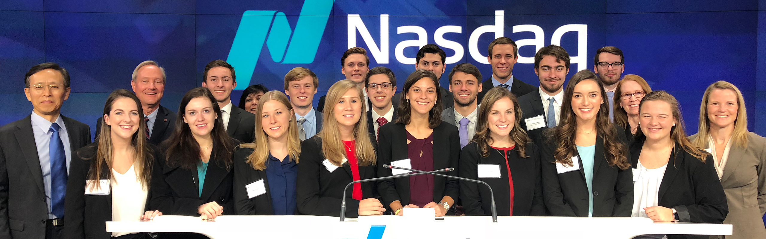 group standing at in front of Nasdaq sign
