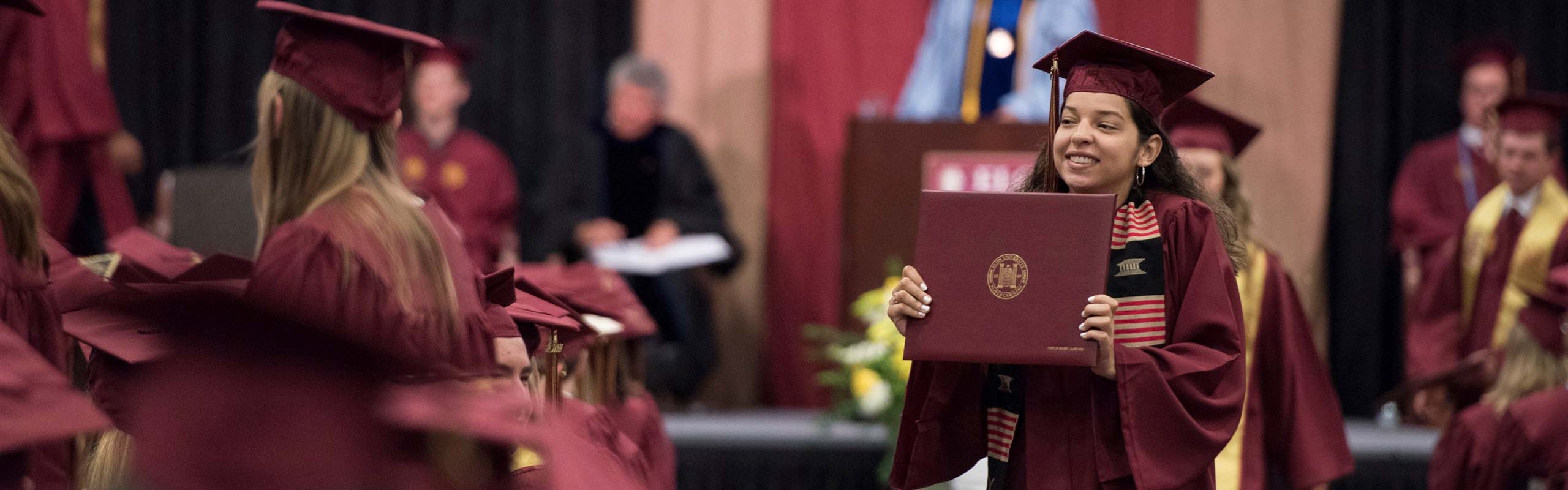 Picture of student holding up diploma at commencement