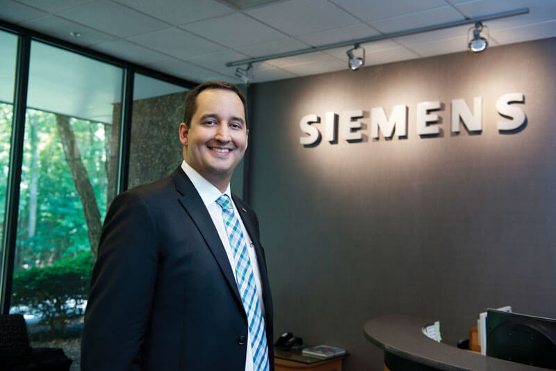 A person standing in front of a wall that reads Siemens.