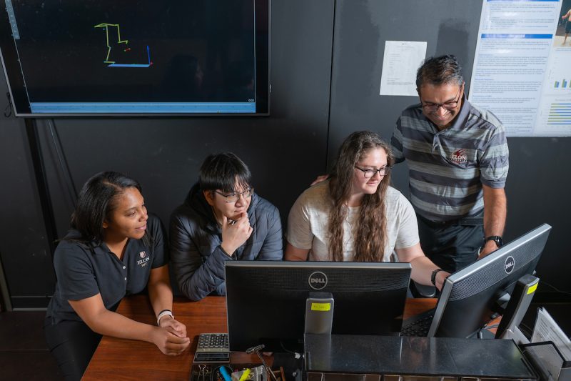 Elon students looking a computer