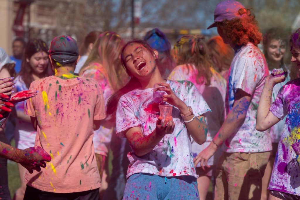 A large group of students covered in color powder for Elon's Holi celebration.