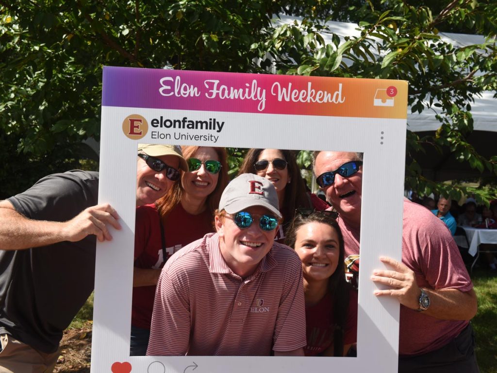 A family poses for a photo with an Instagram frame photo prop during Elon's Family Weekend.