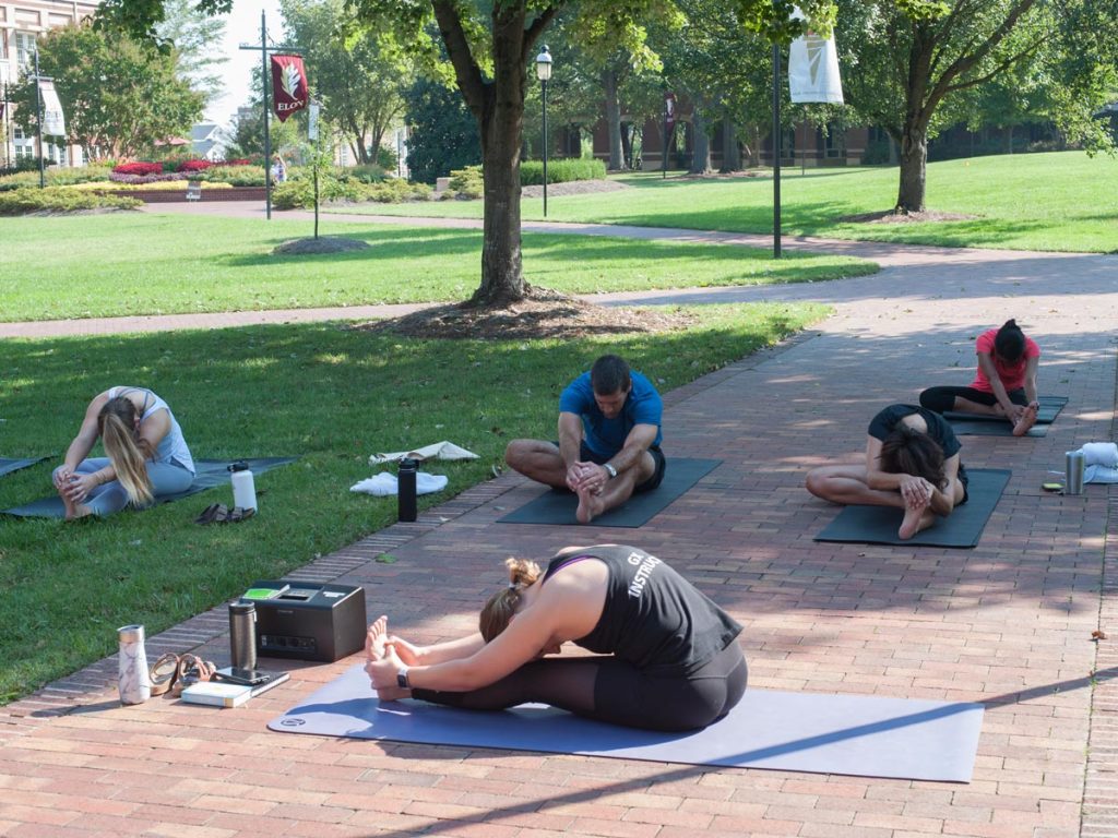 Families participate in a yoga 'class on the grass' organized by Campus Rec during Family Weekend.