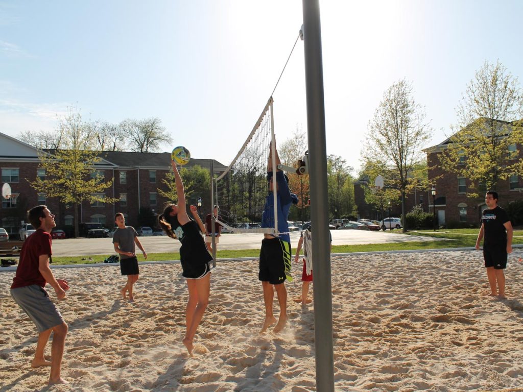 A group of students playing sand volleyball.