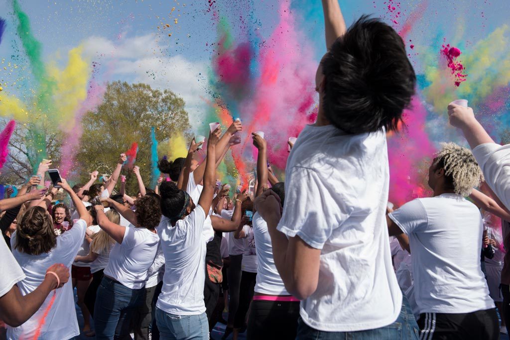 Elon students throwing colored powder at one another to celebrate Holi, the Hindu festival of colors.