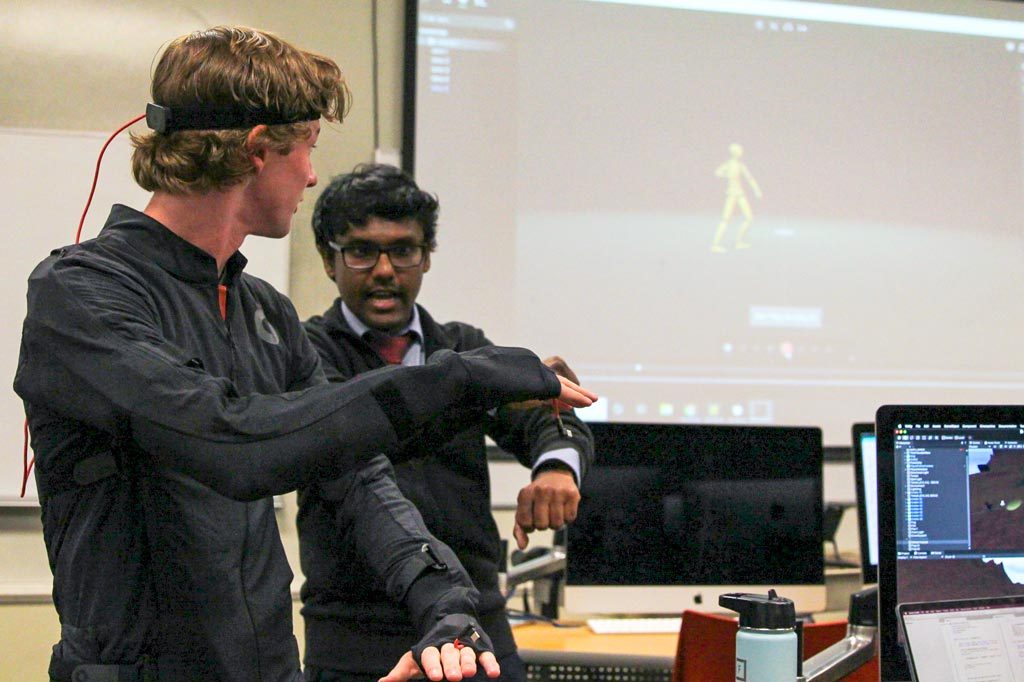 An Elon professors works with a student wearing a motion capture suit.