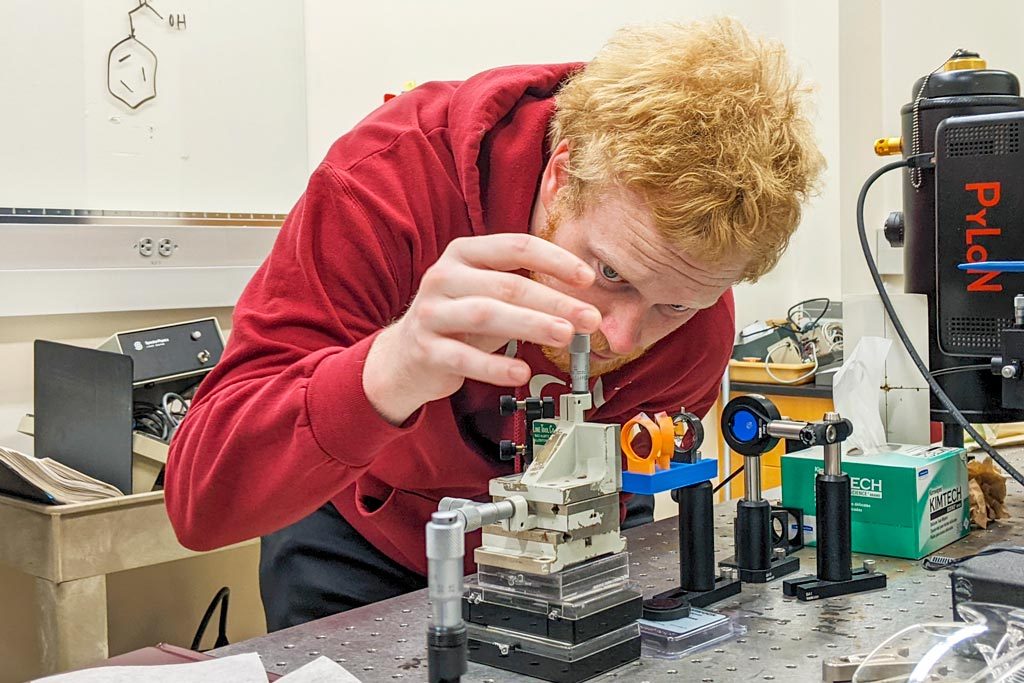 A student tinkers with a machine in an engineering lab.