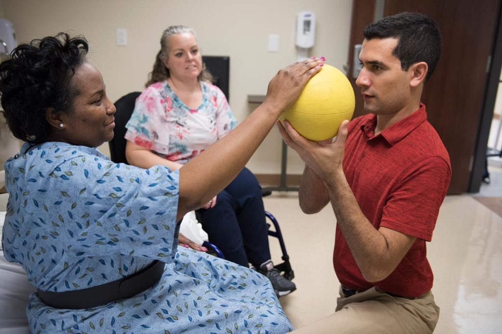 A physical therapy student working with an actor portraying a patient during a clinical simulation.