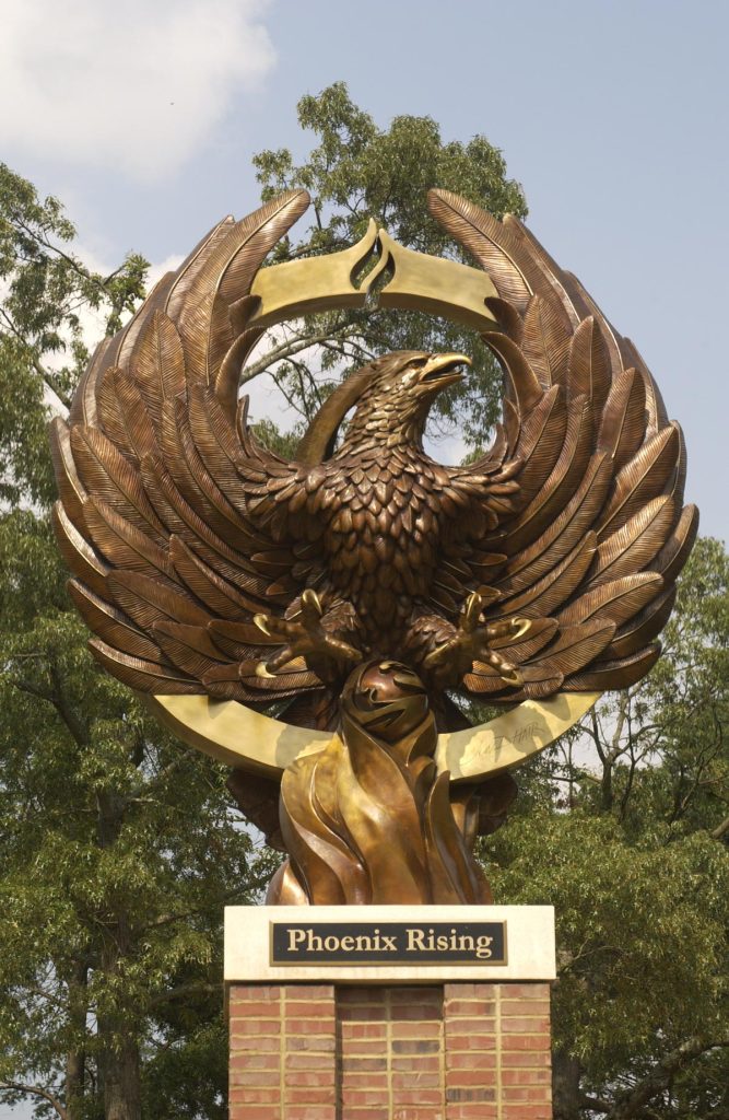 A 19-foot bronze sculpture of a Phoenix sits atop a brick column adorned with a plaque that reads "Phoenix Rising".
