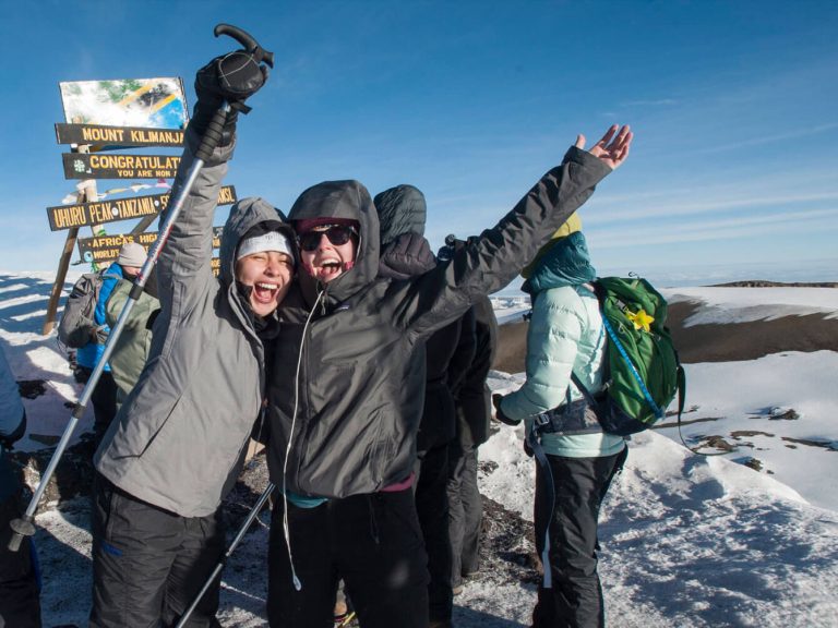 A group of Elon students celebrates making it to the top of Mount Kilimanjaro