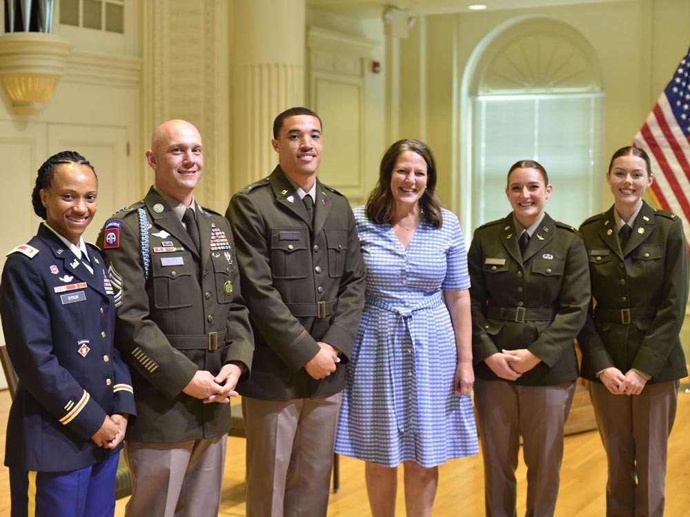 During the U.S. Army ROTC commissioning ceremony, three graduates stand alongside Elon's president on the stage in Whitley Auditorium. Accompanying them are two officers who delivered remarks at the ceremony.