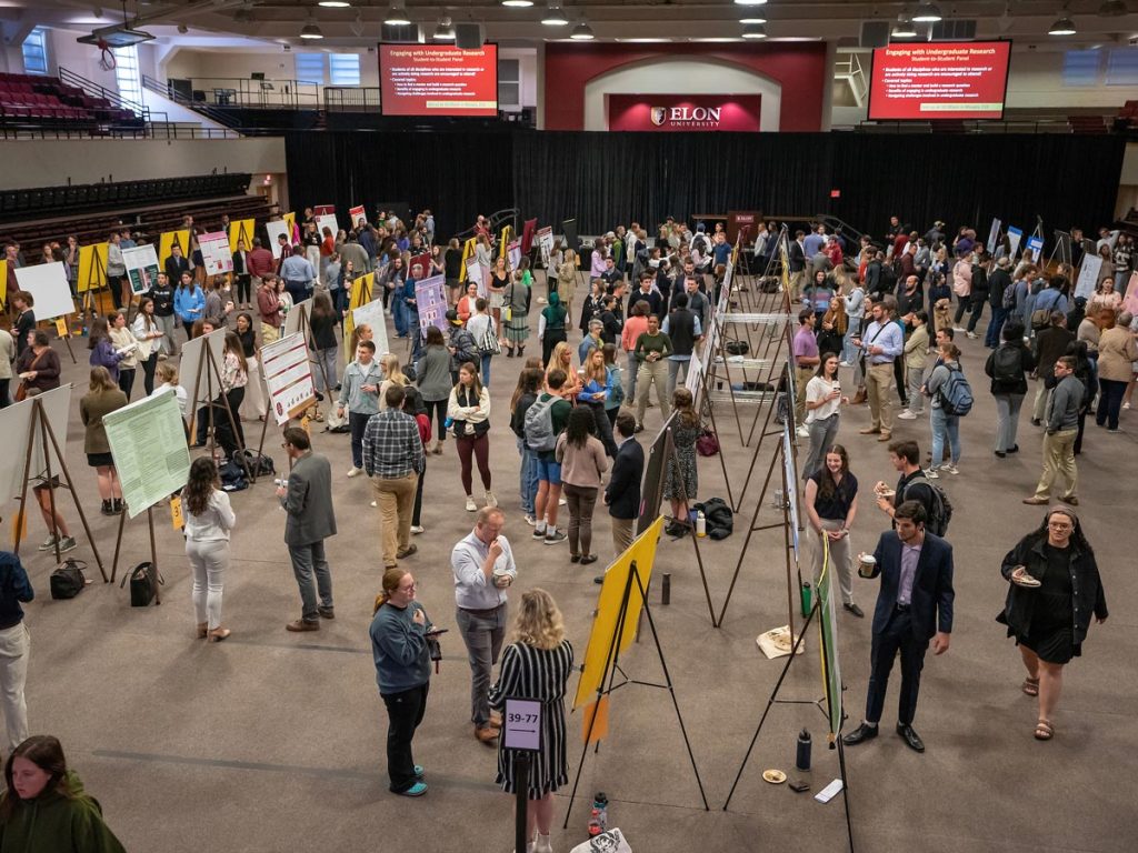 A substantial gathering of Elon students, faculty, and staff congregates in Alumni Gym for one of two poster sessions during the annual Spring Undergraduate Research Forum.