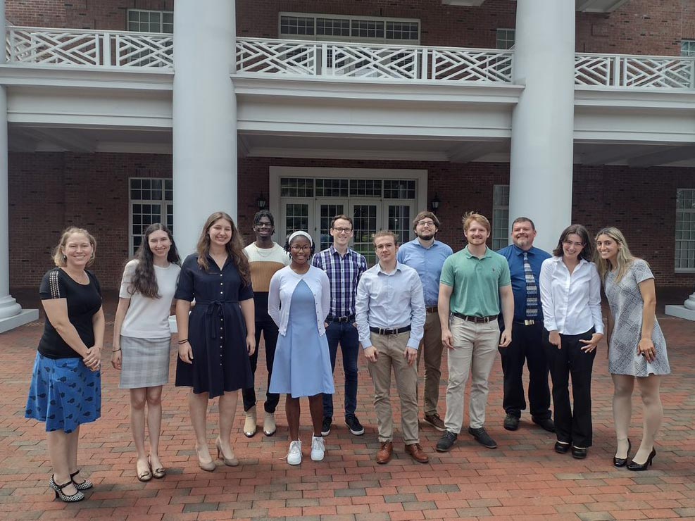 Students and faculty gather for a photo in front of a brick building on Elon's campus during the National Science Foundation-funded 2022 North Carolina A&T State University and Elon University Joint Research Experiences for Undergraduates in Mathematical Biology.