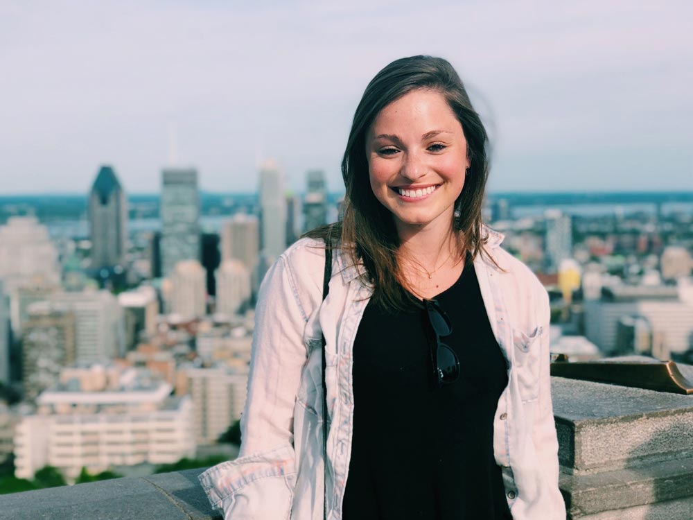 Danielle Cooke smiles for the camera against the backdrop of a cityscape.
