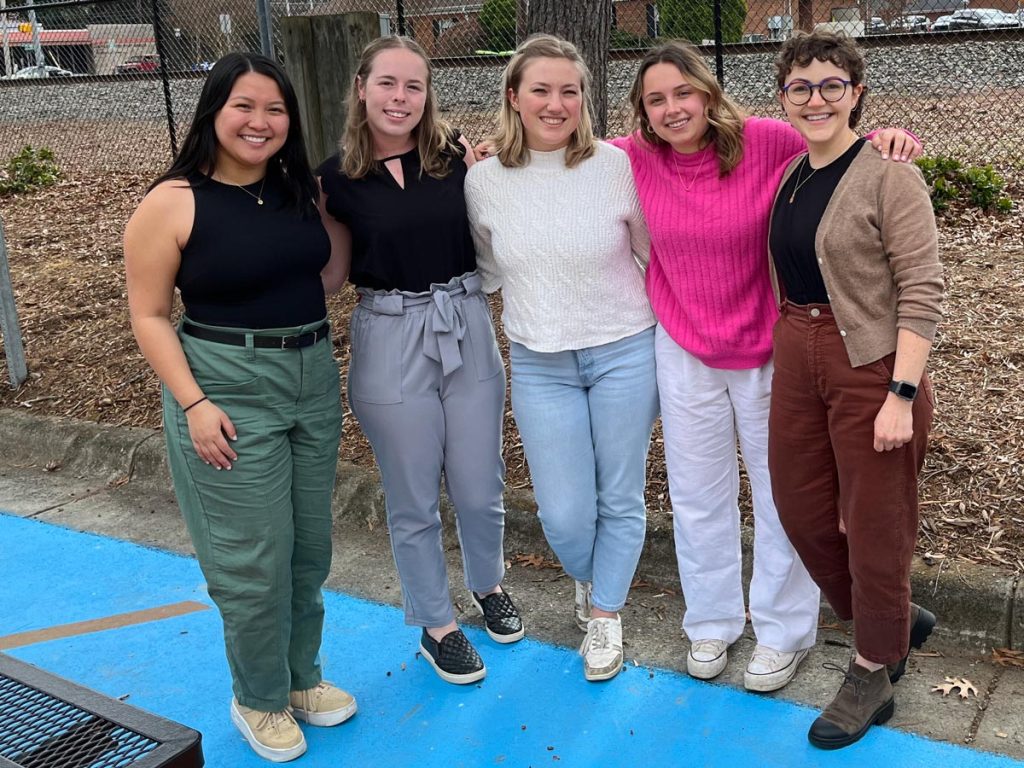 Associate Professor of Psychology Sabrina Thurman poses for a photograph with four psychology undergraduates in downtown Elon.