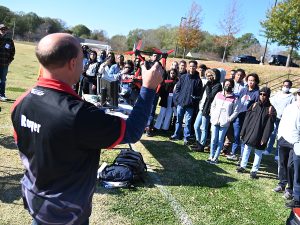 A crowd of students looks on as a drone instructor holds up a drone.