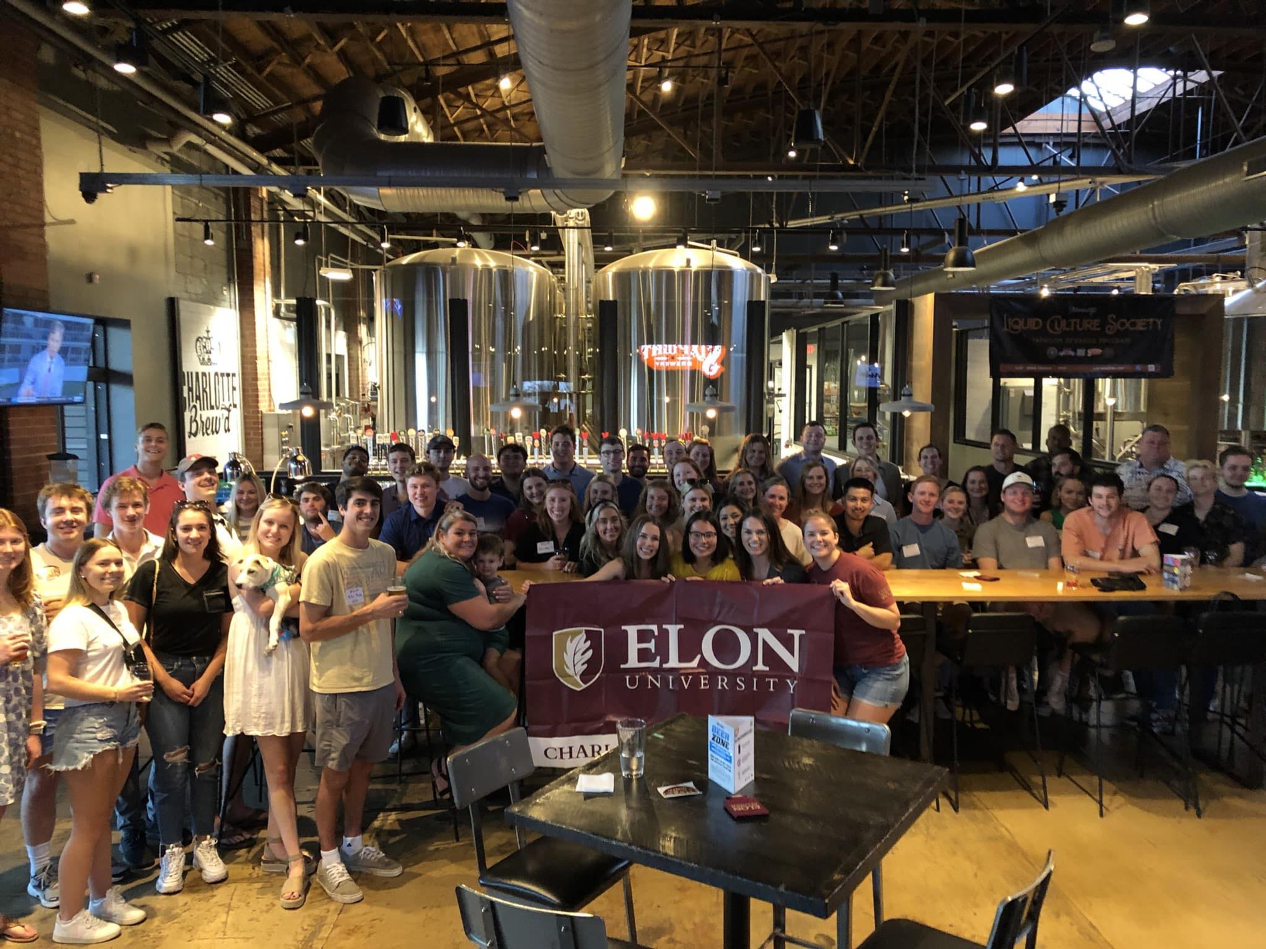 A group photo of participants in a venue holding an elon flag