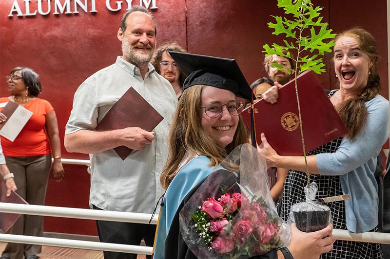 an Elon graduate student holding a sapling, part of a tradition