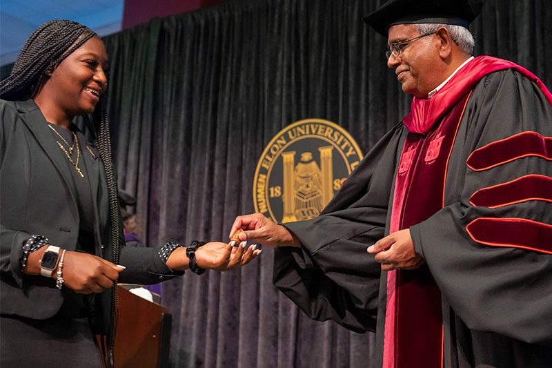 Dean Raghu Tadepalli handing an acorn to a new graduate student at convocation