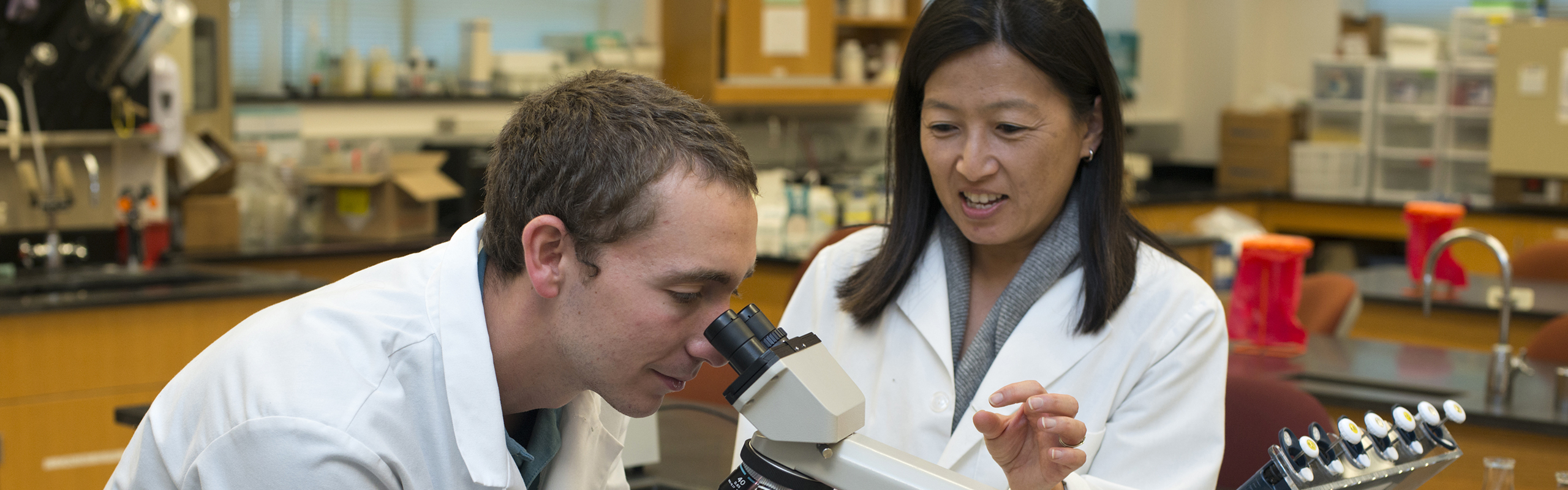 Biology major Zachary Fisher '16 poses in a lab with Yuko Miyamoto, an associate professor of biology.