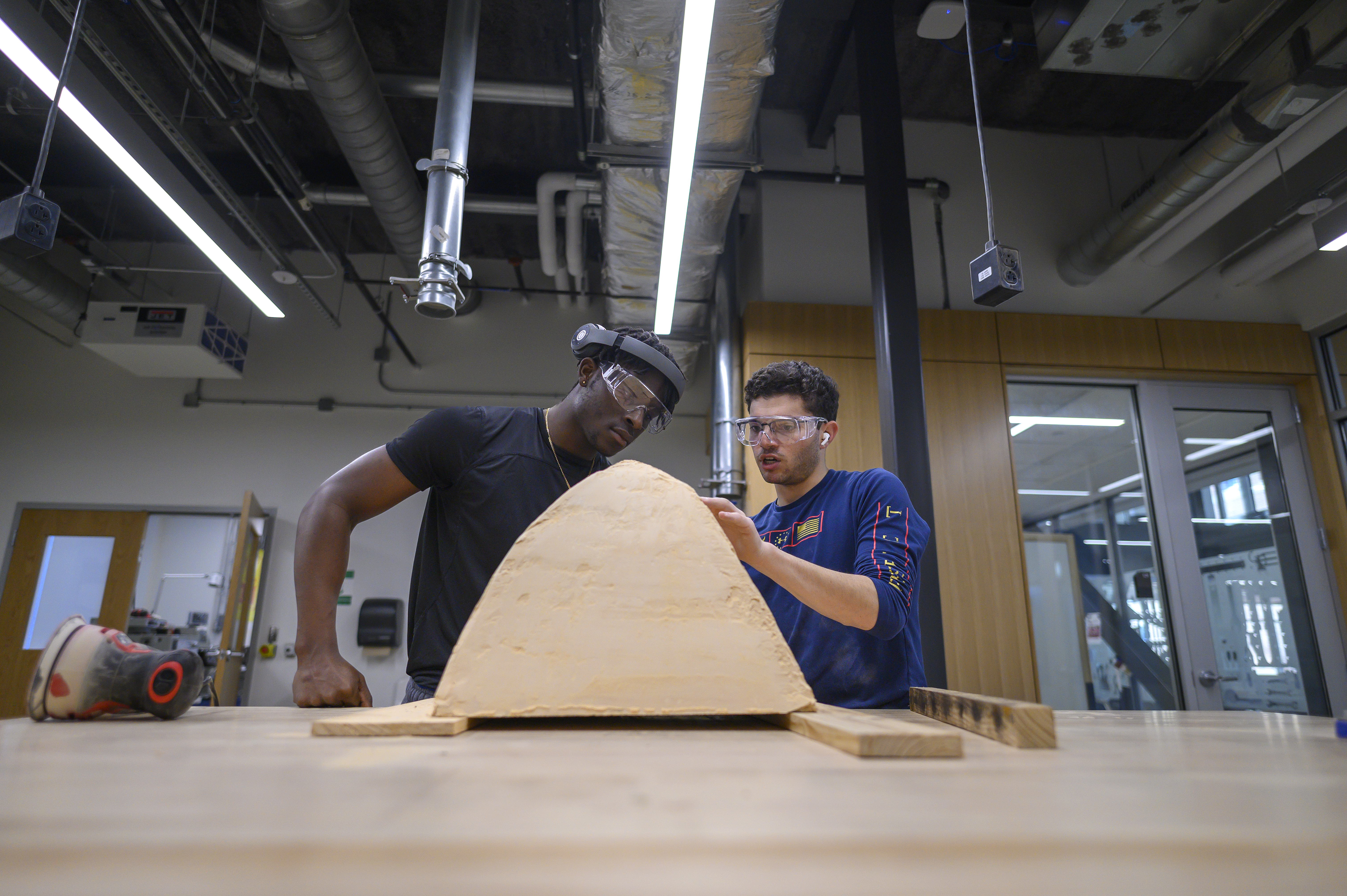 Two male students work in a machine shop building components for a race car